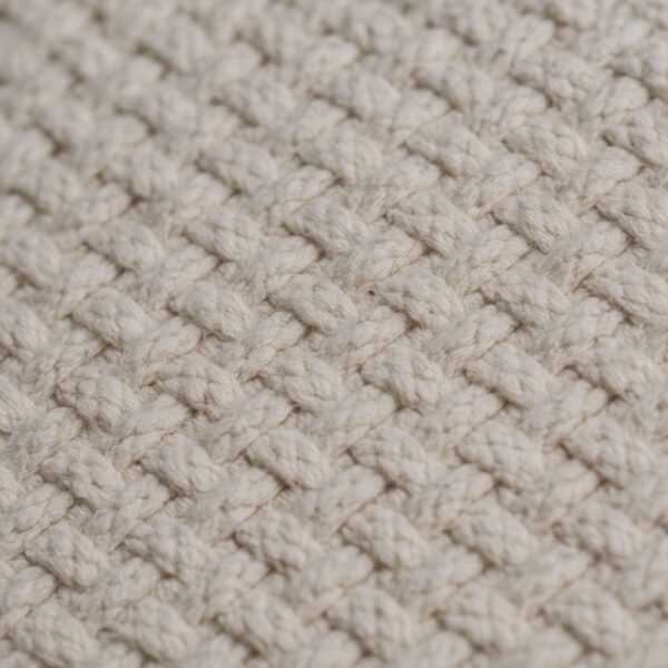 Fehér pamut párna ferde szögből fotózva, természetes szövésmintázattal és enyhe szabálytalanságokkal, közeli textúrafotóban